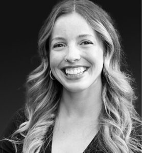 Professional black and white headshot of a woman with long hair and dark shirt.
